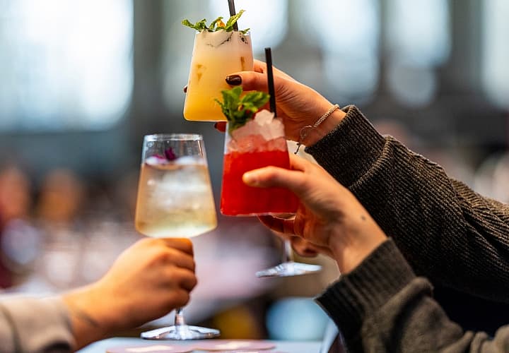 Drie mensen proosten met kleurrijke cocktails tijdens een evenement