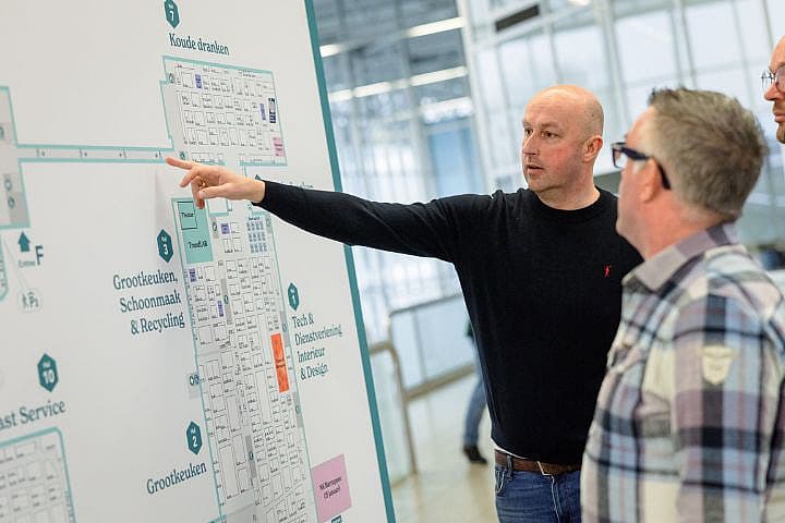 Bezoekers bekijken en wijzen naar de plattegrond van Horecava in RAI Amsterdam