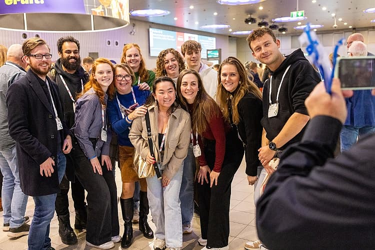 Groep jonge professionals en studenten poseert lachend samen tijdens een horecabeurs.