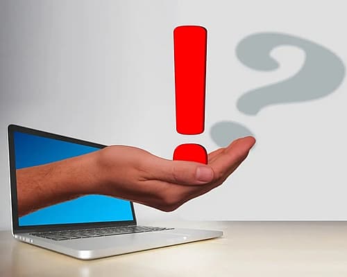 Hand die uit een laptopscherm komt met een rood uitroepteken, en een grijs vraagteken op de achtergrond - symbool voor online hulp of digitale waarschuwing