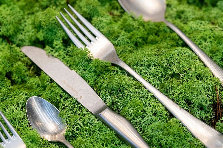 Vorken, messen en lepels liggen op een ondergrond van groen mos