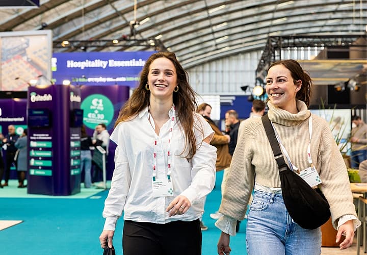 Twee beursbezoekers lopen lachend door een hal tijdens Horecava