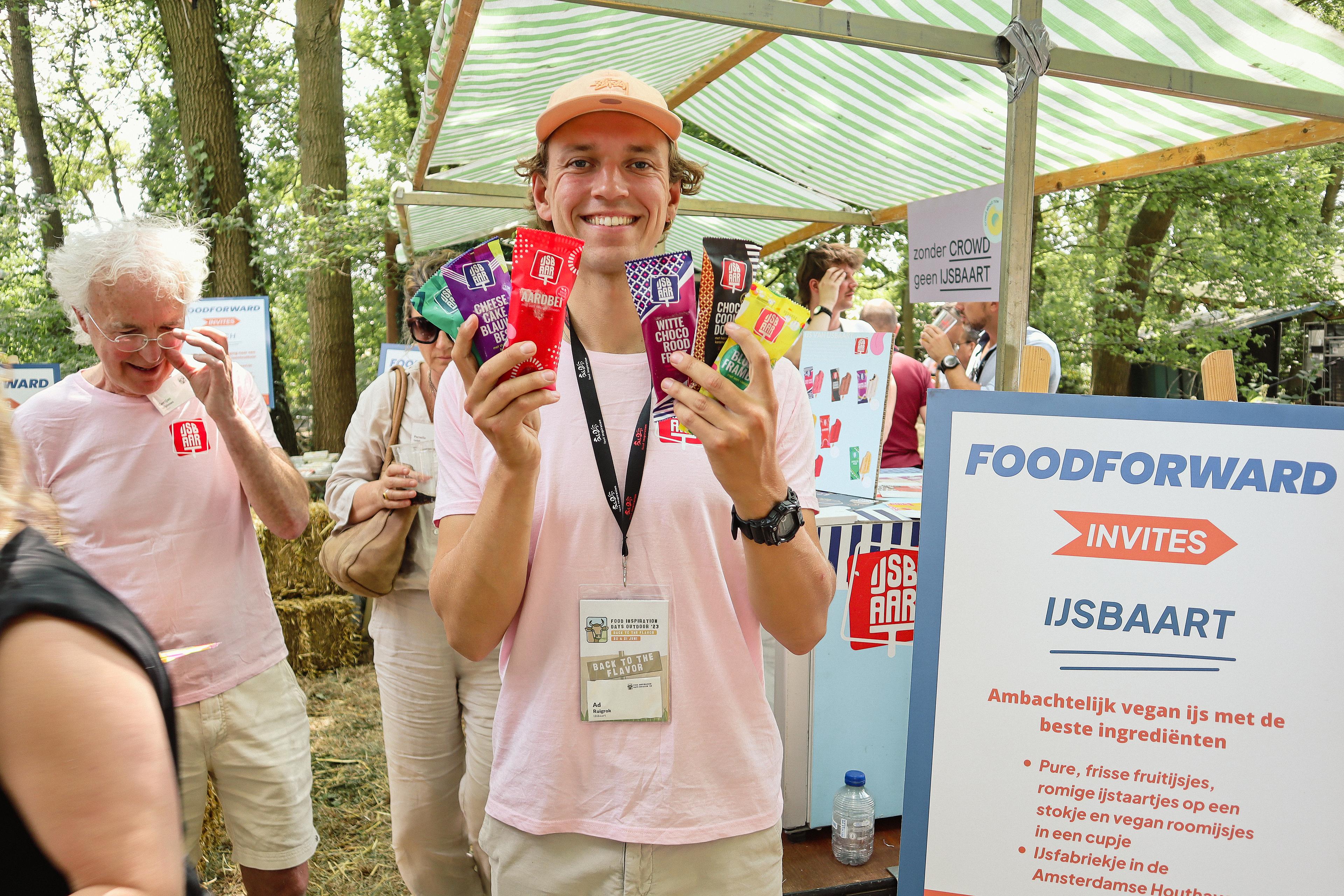 Lachende man die met vegan ijsjes in zijn handen staat.