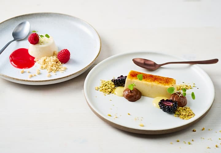 Panna cotta en crème brûlée met fruit, saus en crumble op lichte borden